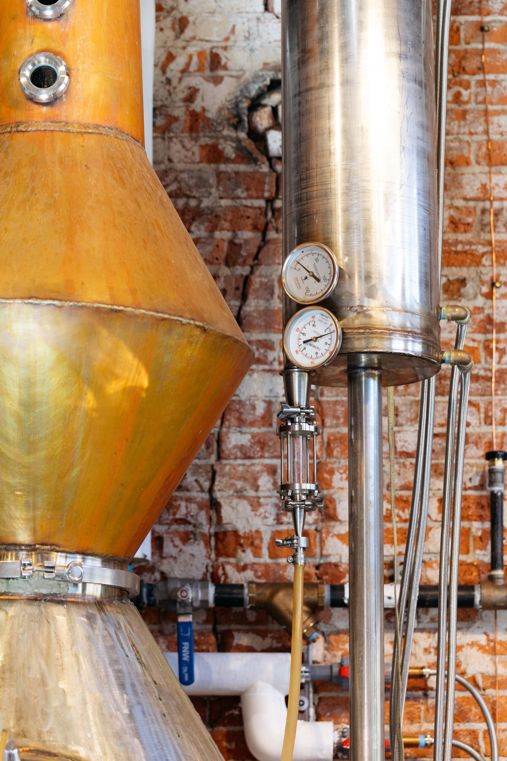 Brewery distiller in front of a brick wall.