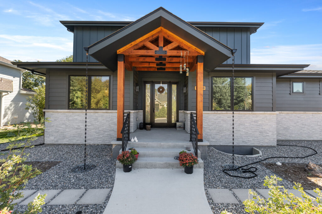 The exterior of a black house with brown support beams in the entrance.