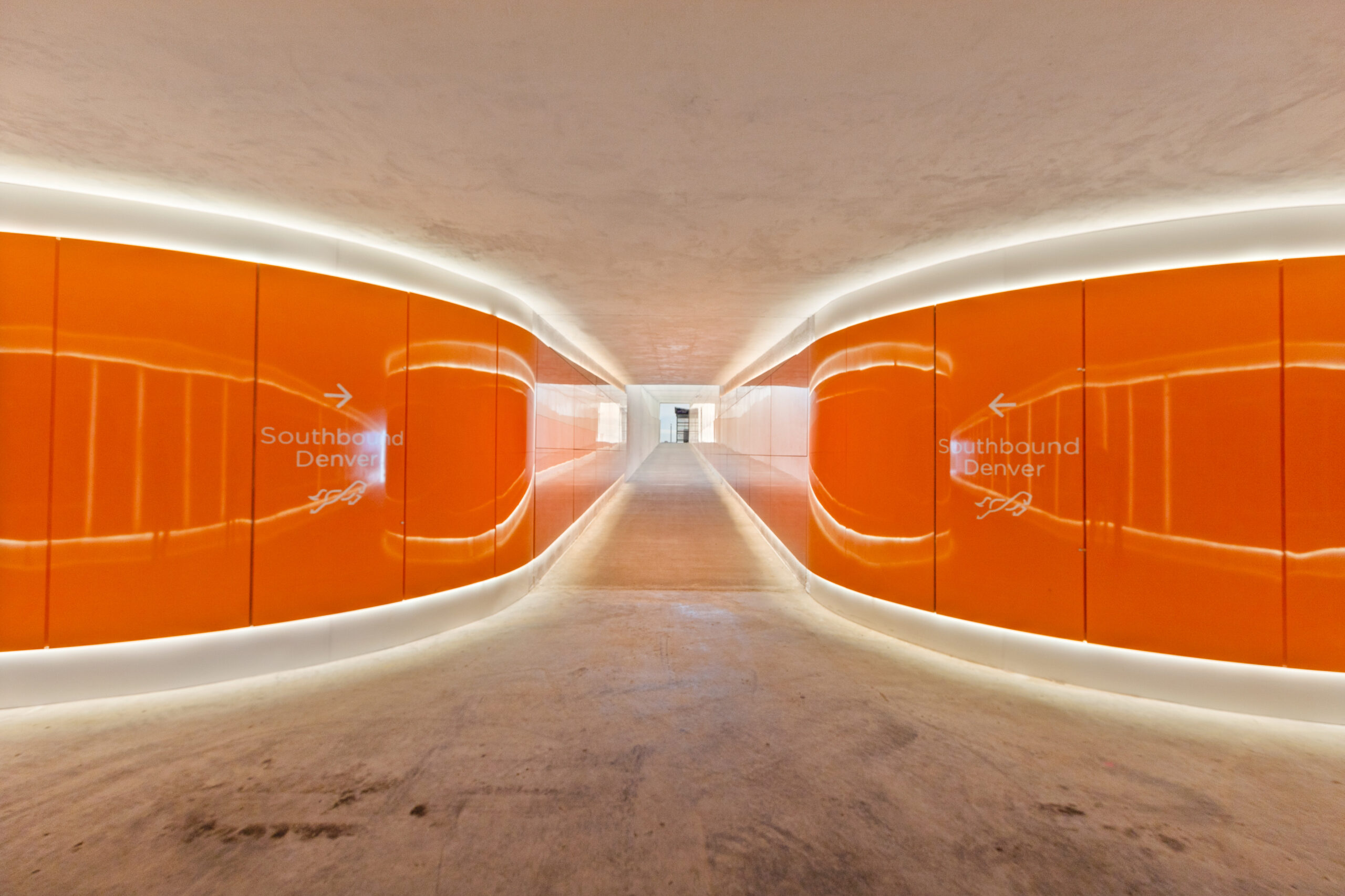 A brightly lit tunnel with orange panels along the walls.