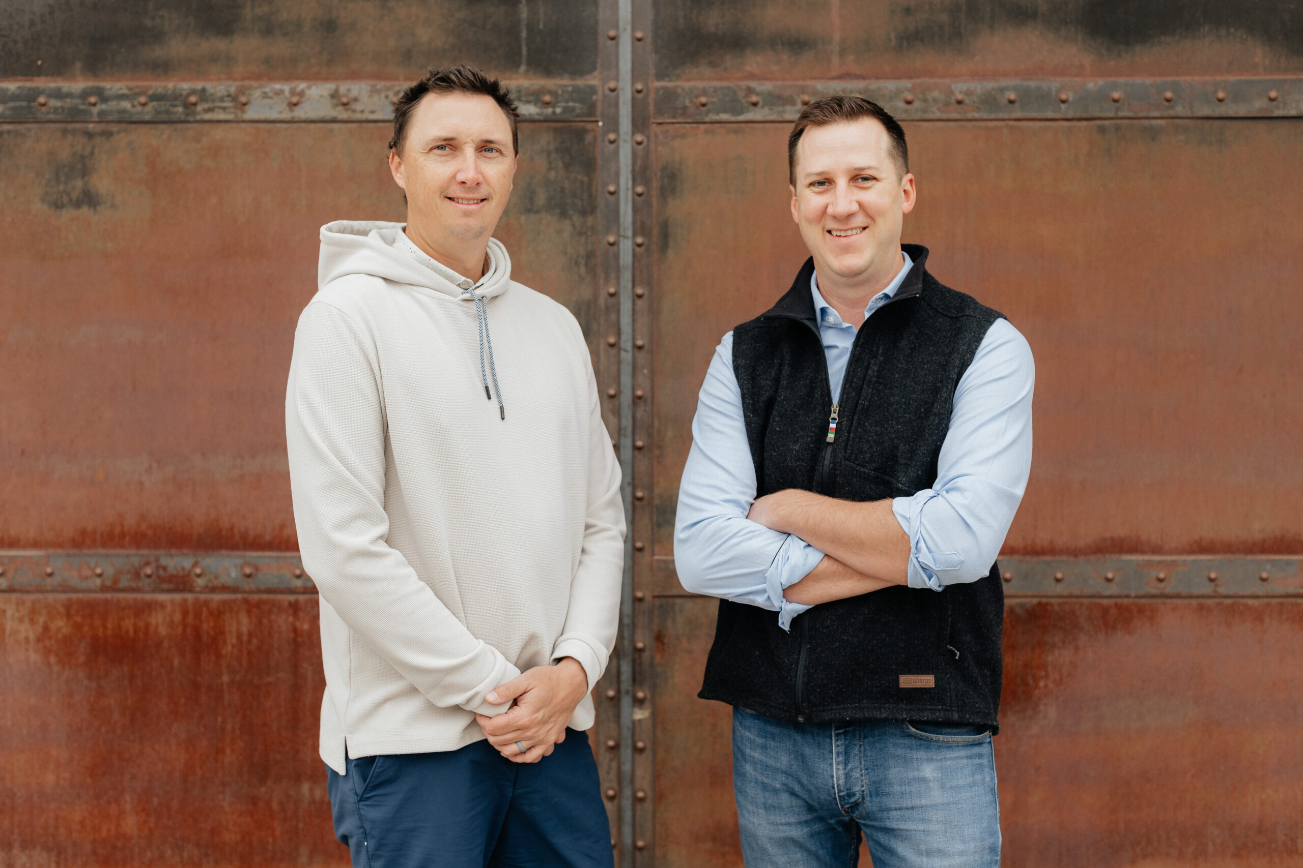 Cory Jennings and Beau Brittenham standing in front of a metal wall smiling into the camera.